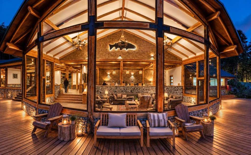The timber-frame lodge lit at dusk, seen from the deck